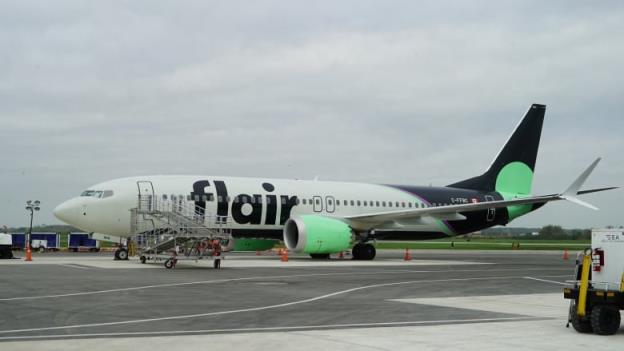An airplane with navy blue and sea green accents, with the word 'FLAIR' on its side.