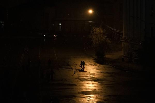 People walk across a street during a blackout in Kyiv, Ukraine, Sunday, Nov. 6, 2022.