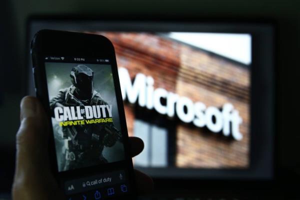 An image from Activision's Call of Duty is shown on a smartphone near a photograph of the Microsoft logo in this photo taken in New York, Thursday, June 15, 2023. 