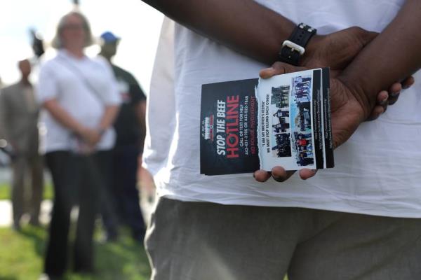 A member of We Our Us Movement holds flyers prior to a "community walk" to show support in the Brooklyn Homes neighborhood on July 3, 2023 in Baltimore, Maryland. Two people were killed and dozens injured, many of them minors, during a mass shooting at a block party in the South Baltimore neighborhood.