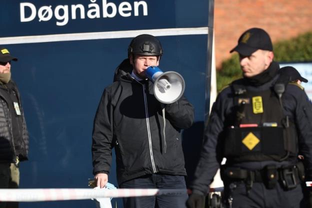 A man in a helmet speaks into a megaphone in front of a mosque in Copenhagen, Denmark.
