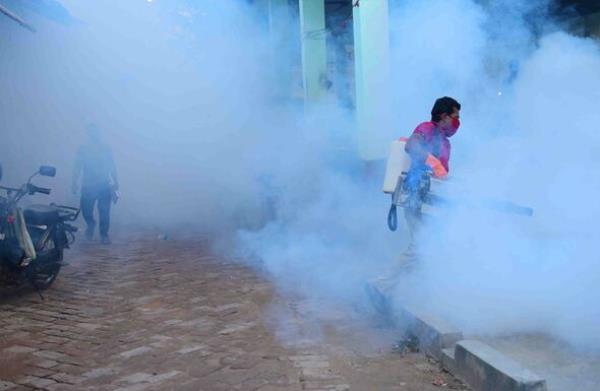 A worker fumigates a market area as a preventive measure against mosquito-borne diseases on World Malaria Day