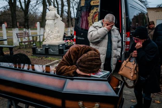 Mourners reach at a coffin.