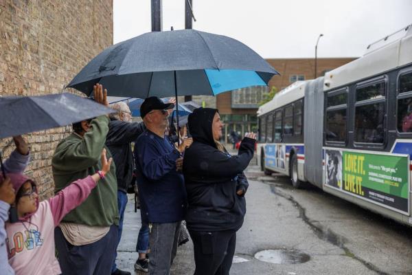 Rogers Elementary School teacher Erin Armstrong, 40, center, waves with members of the community as a CTA bus leaves the High Ridge YMCA shelter  in Chicago to transfer migrants to Daley College on Tuesday, June 13, 2023.