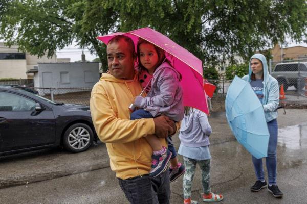 Edgar Alexander Roa, 44, of Venezuela, carries his 4-year-old daughter Paulet Morales before the two are transferred by a CTA bus from the High Ridge YMCA migrant shelter to Daley College on June 13, 2023.