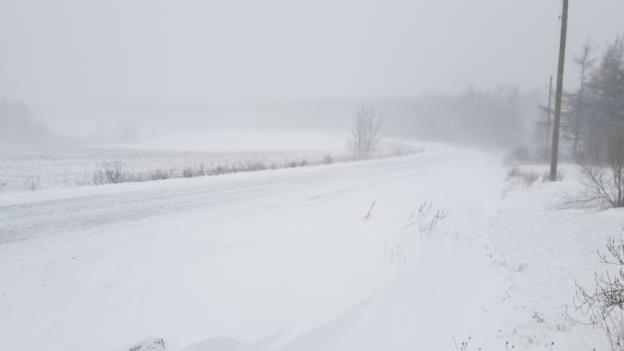 A snowy road with limited visibility is shown in a rural area of Nova Scotia.